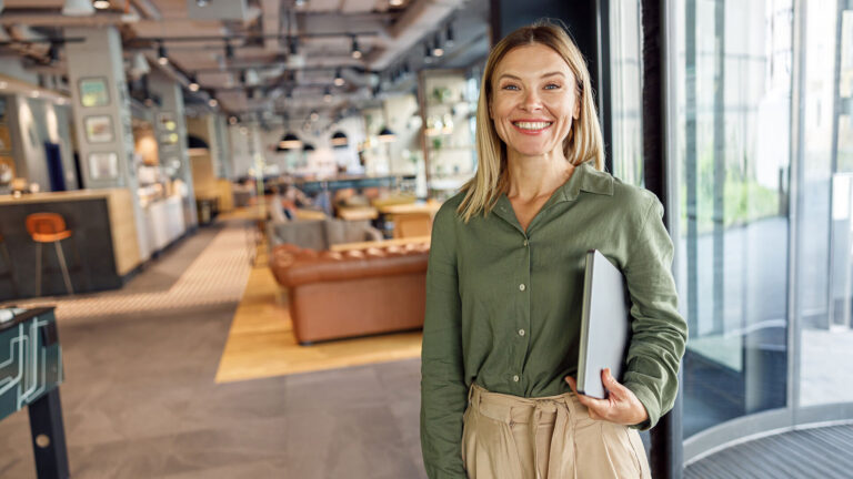 business woman happily looking at the camera with a laptop under her arm - ,Ganttic resource planner